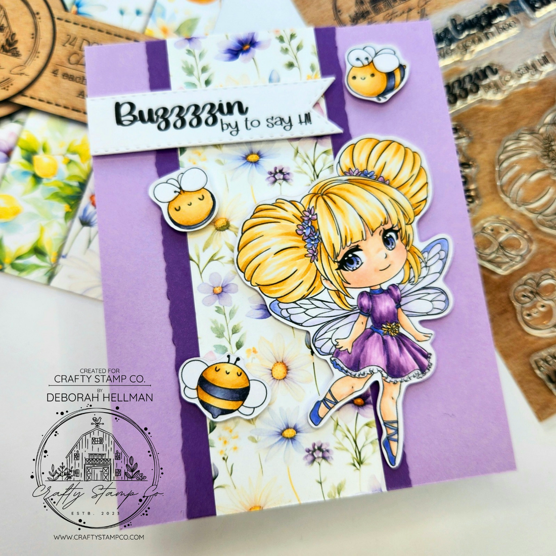 Handmade spring card by Deborah Hellman featuring Buzzy Bee Meadow with blonde hair, purple dress, and tiny bee accents layered over floral patterned paper.