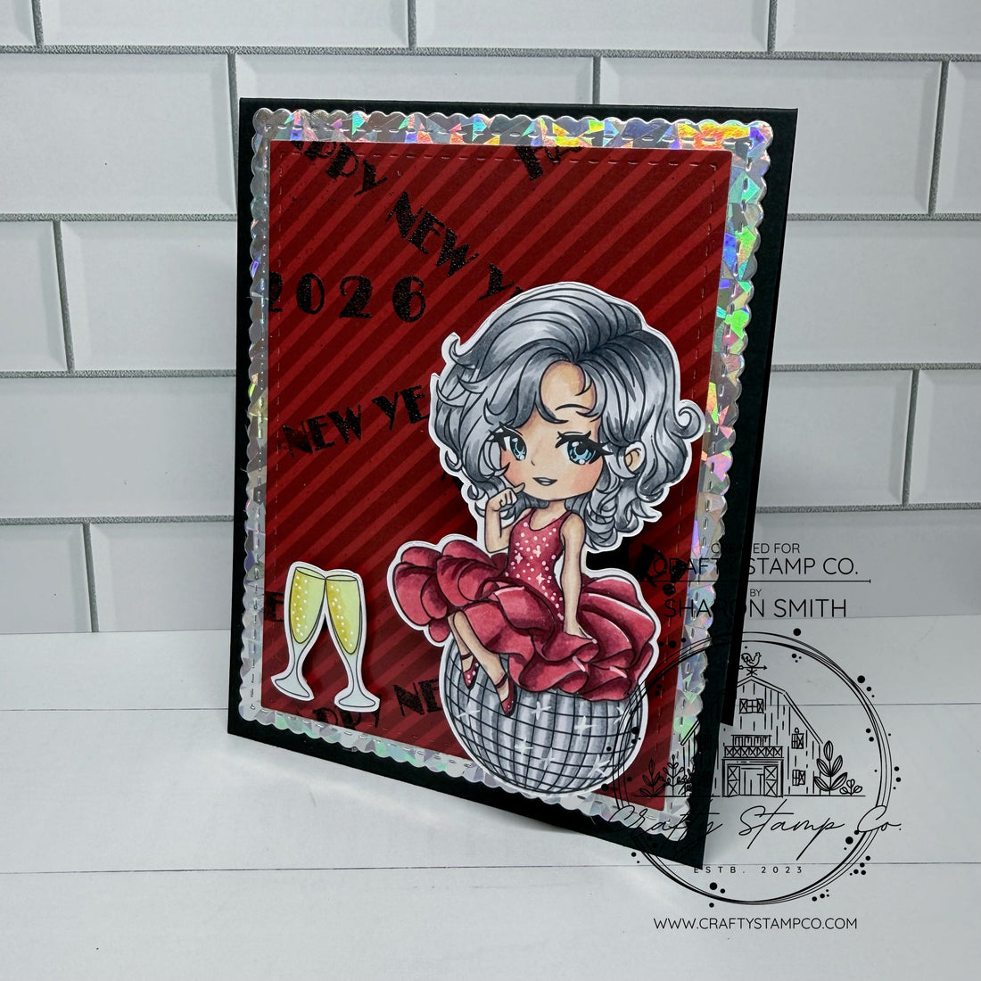 Handmade New Year card featuring a girl sitting on a disco ball, holographic border, red patterned paper, and champagne glasses—created by Sharon.