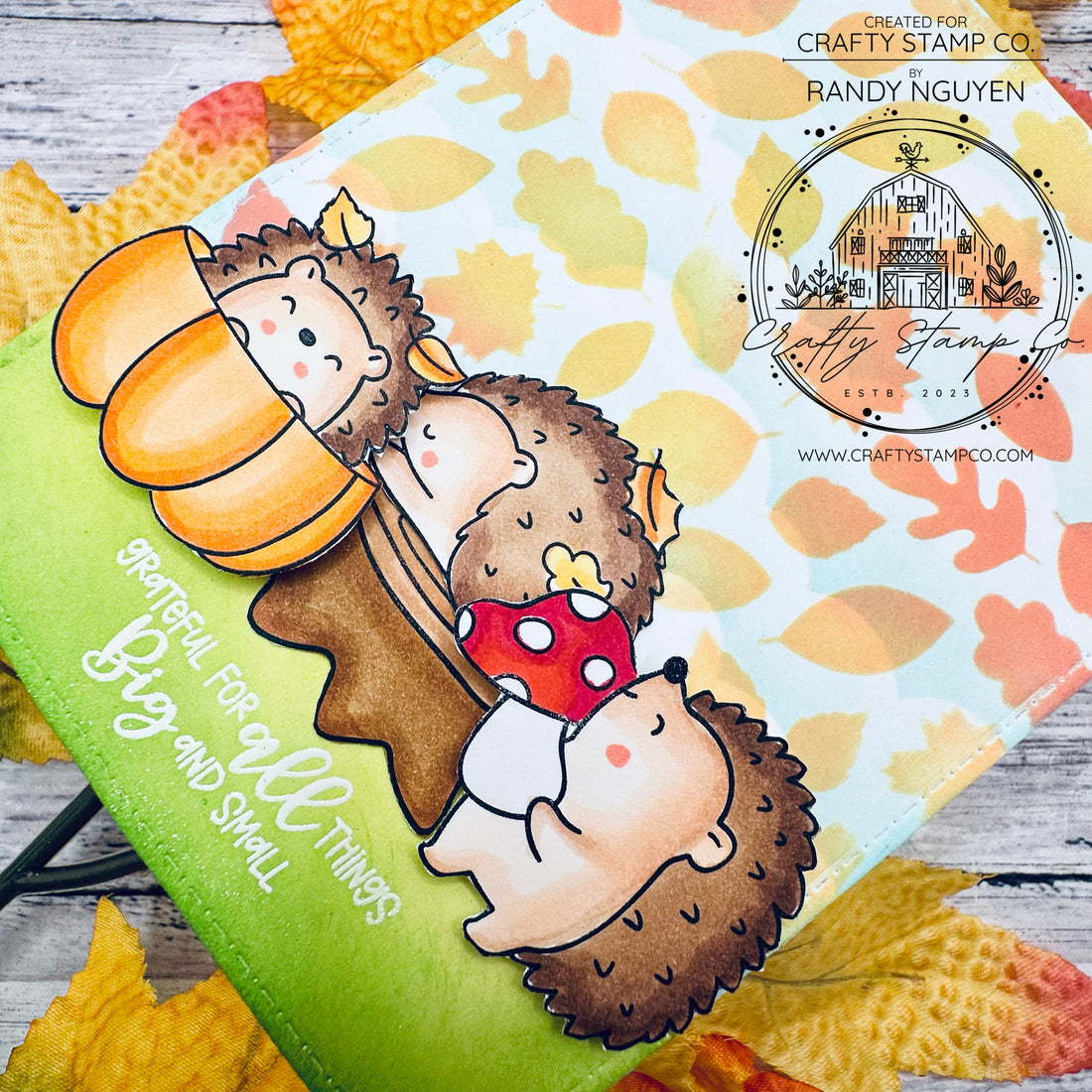 Handmade fall card featuring three cute hedgehogs from the Fall Hedgies stamp set, nestled in a pumpkin and tree stump with a stenciled leaf background and “grateful for all things big and small” sentiment.