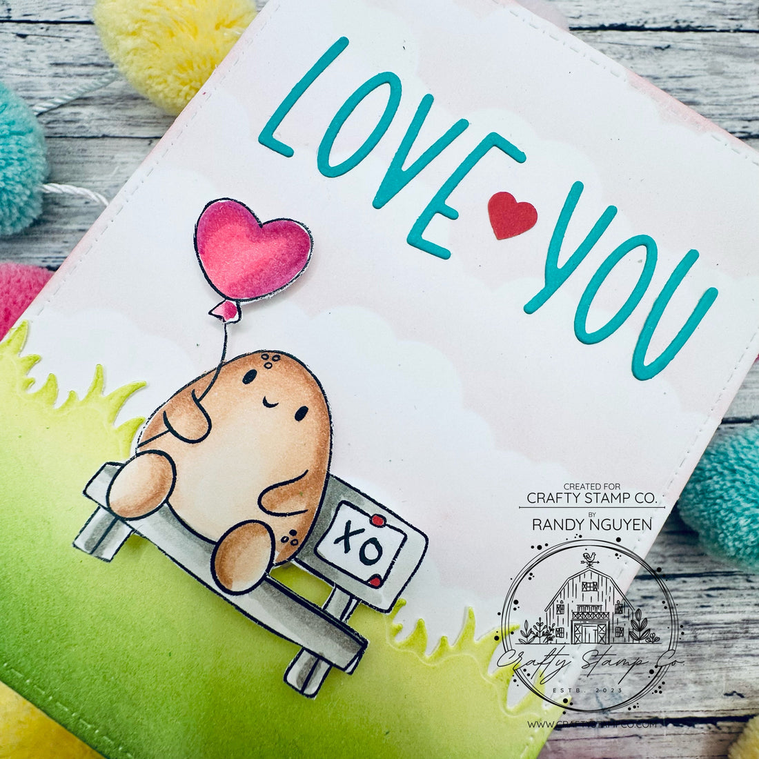 Handmade Valentine card featuring Tate from Positive Tates Love Notes sitting on a bench with a heart balloon and “LOVE ❤️ YOU” die cut letters above, created by Randy Nguyen for Crafty Stamp Co.