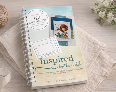 Notebook titled 'Inspired by the Sketch' on a light wooden surface with yarn and flowers.